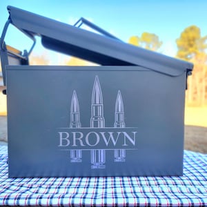 May include: A gray metal ammo can with a hinged lid. The can has a white design of three bullets with the word "BROWN" printed below them.