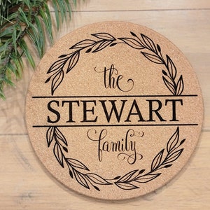 May include: A round cork trivet with a black wreath design and the text "the STEWART family" in a cursive font.