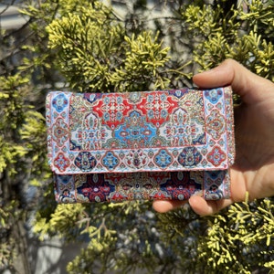 May include: A small red, blue, and gold patterned wallet with a geometric design.