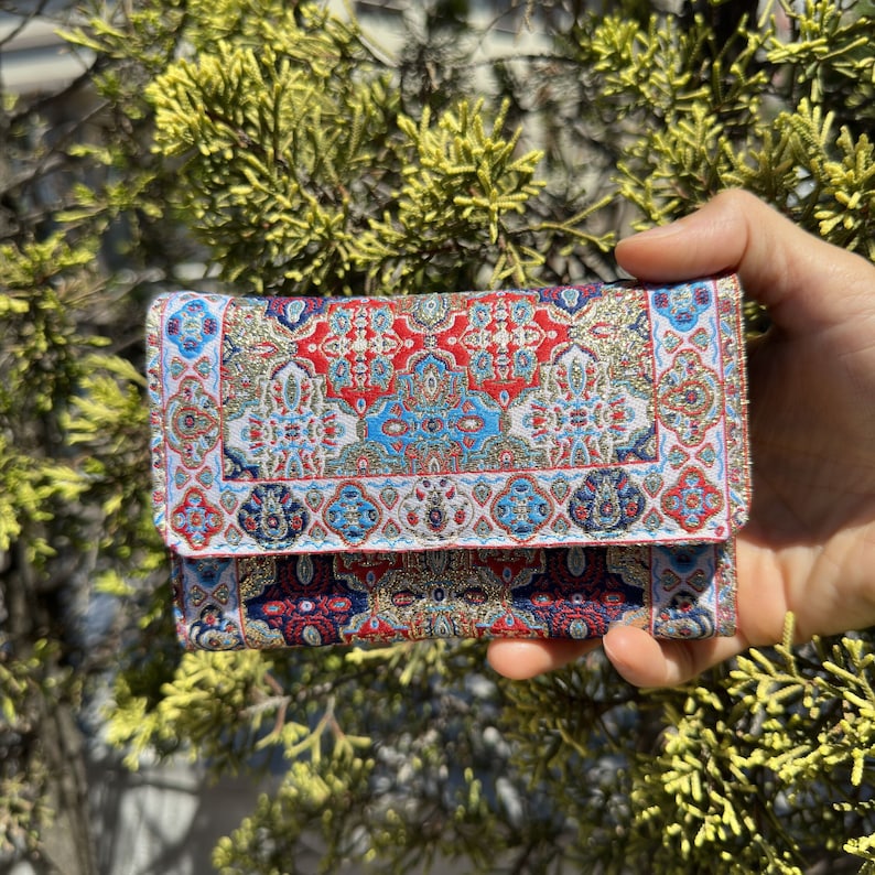 May include: A small red, blue, and gold patterned wallet with a geometric design.