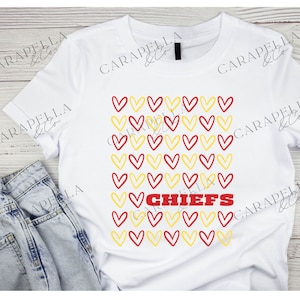 May include: White t-shirt with a red and yellow heart pattern and the word "CHIEFS" in red letters.