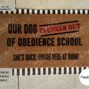 May include: A brown coir doormat with black and white stripes around the edges. The doormat has the text "Our dog flunked out of obedience school. She's back, living here at home." printed in black. The words "flunked out" are in red.