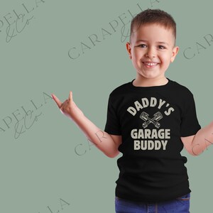 May include: Black t-shirt with a white graphic that says "Daddy's Garage Buddy" with a pair of crossed wrenches.