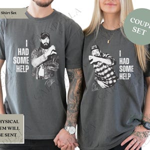 May include: A couple's set of two gray t-shirts with a distressed look. The shirts feature a black and white illustration of a man with the text "I had some help". One shirt has the text "My wife" under the illustration, and the other shirt has the text "I had some help".
