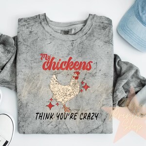 May include: A gray t-shirt with a distressed look featuring a red and white illustration of a chicken with the text "My chickens think you're crazy".