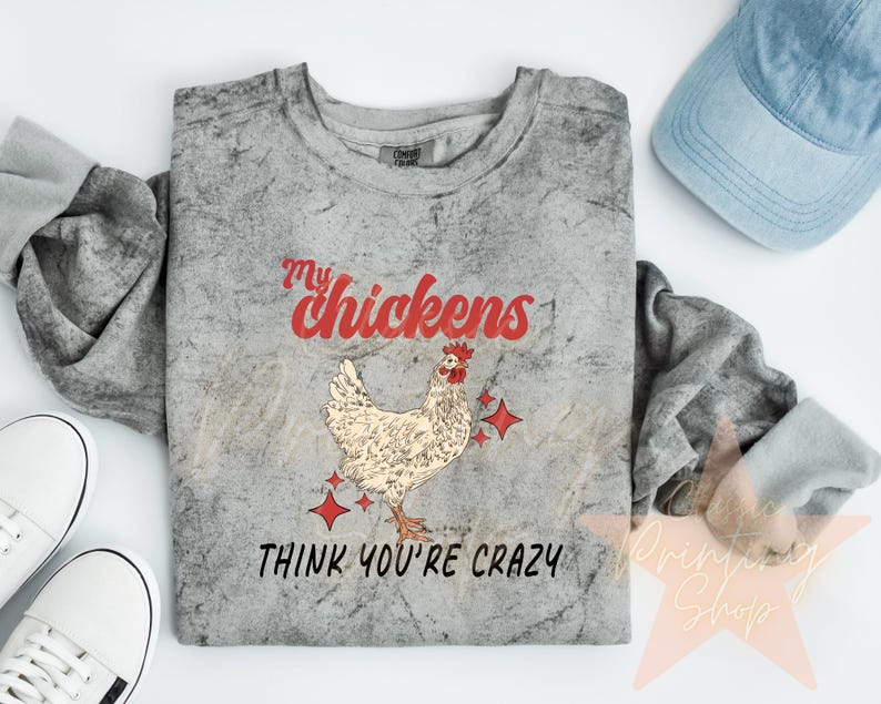 May include: A gray t-shirt with a distressed look featuring a red and white illustration of a chicken with the text "My chickens think you're crazy".