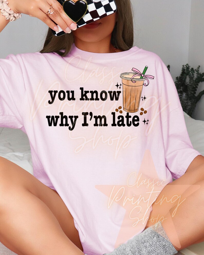 Puede incluir: Camiseta rosa con el texto "you know why I'm late" y una imagen de dibujos animados de una bebida de caf&eacute; con una cinta rosa y una pajita.