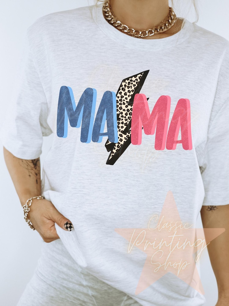 May include: White t-shirt with a blue and pink "MAMA" graphic with a leopard print lightning bolt in the middle.