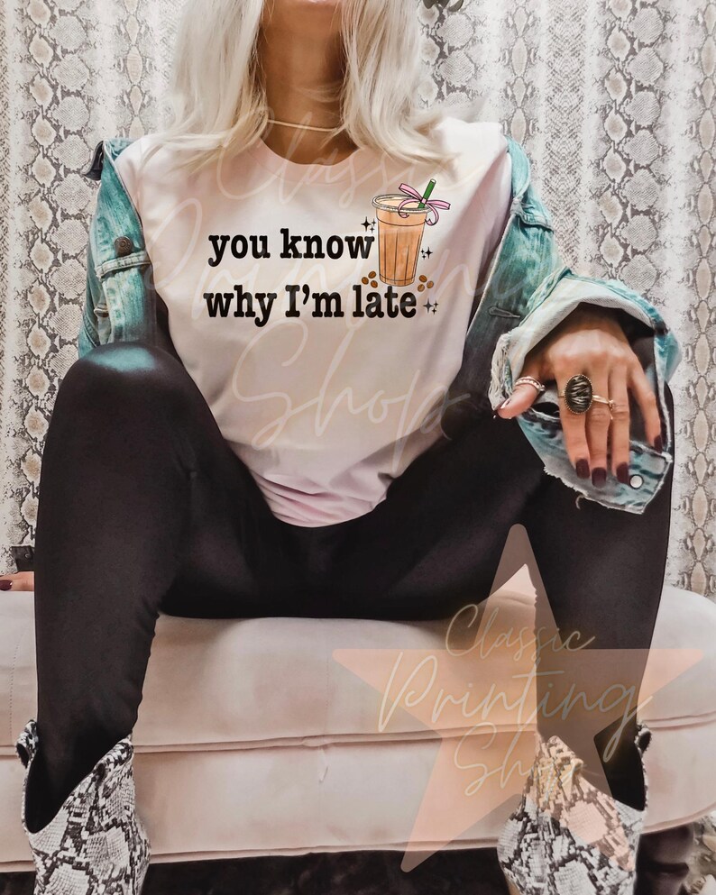 Puede incluir: Una camiseta blanca con el texto "you know why I'm late" y una imagen de dibujos animados de una bebida de caf&eacute; helado con una pajita rosa y espolvoreos.