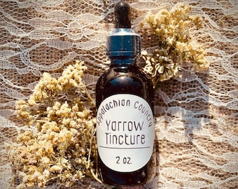 May include: A 2 ounce bottle of Yarrow Tincture from Appalachian Country. The bottle has a white label with black text. The bottle is sitting on a white lace fabric.