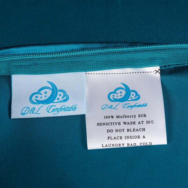 May include: White care label with blue text and a logo that says "DOL Comfortable" and instructions for washing 100% mulberry silk. The label is on a teal fabric background.