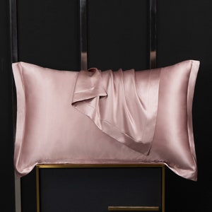 May include: A blush pink silk pillowcase with a folded edge. The pillowcase is made of soft, luxurious silk and is designed to help prevent wrinkles and hair breakage.