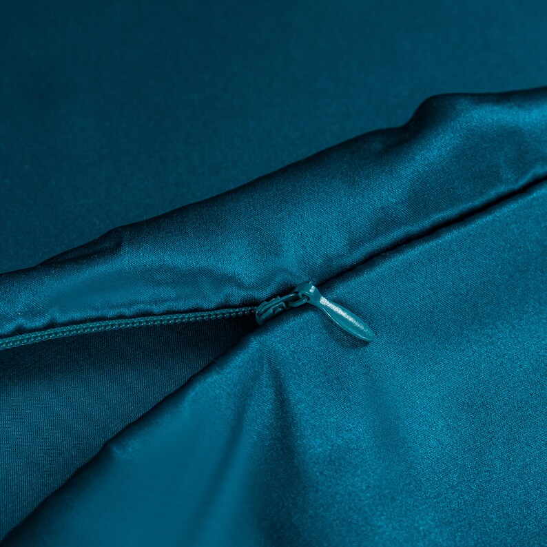 May include: A teal blue satin pillowcase with a zipper closure.