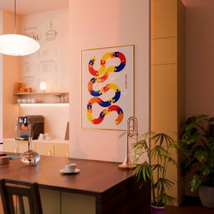 May include: A framed vertical wall art print featuring a winding, snake-like abstract shape composed of interconnected yellow, red, and blue circular segments with small dots, displayed on a wall with the text magic carpet 72 printed on the side.