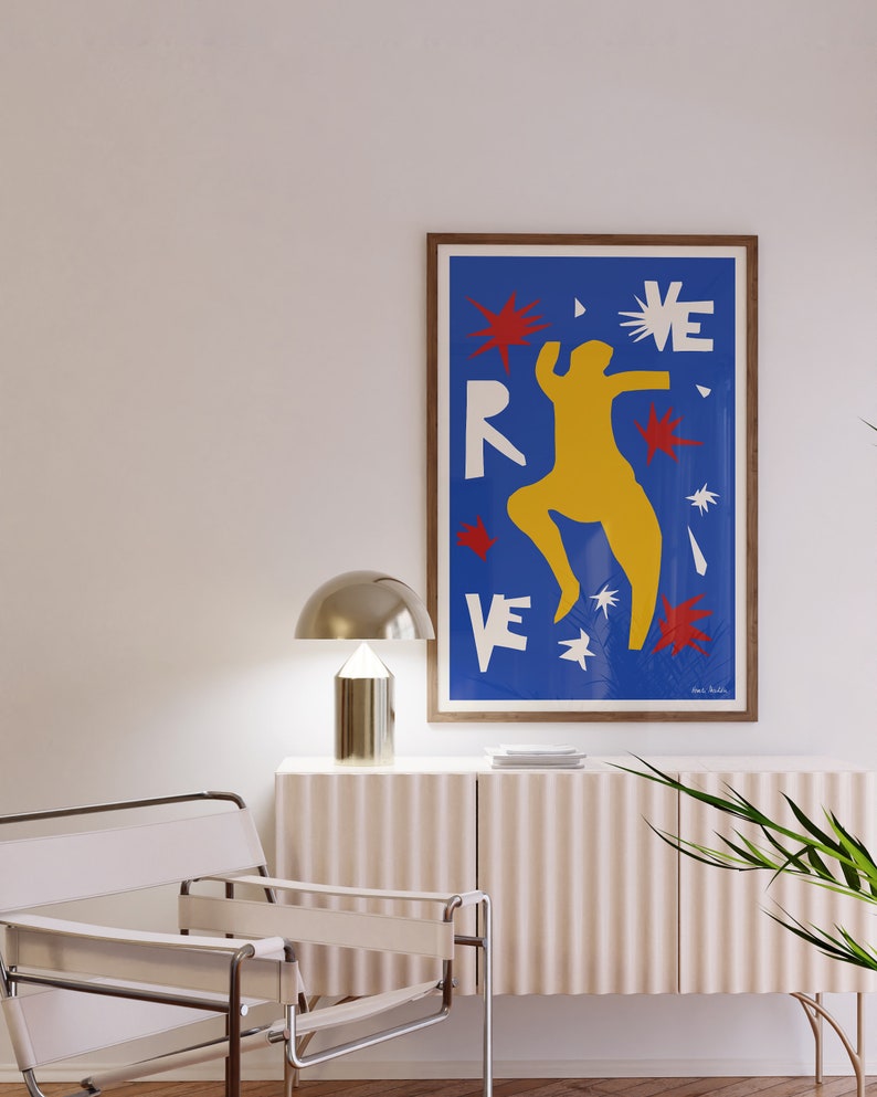 May include: A framed poster with a blue background and a yellow figure dancing. The poster has the word "REVE" in white letters and red and white stars.