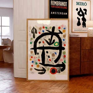 Peut inclure: Impression d'art abstrait avec un motif noir et blanc avec des points et des lignes colorés sur un fond beige. L'impression est encadrée dans un cadre en bois clair.
