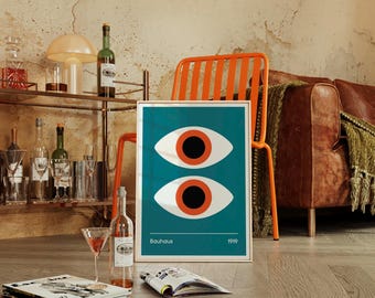 May include: A framed Bauhaus art print featuring two stylized eyes with orange irises on a teal background. The print is displayed near a bar cart with bottles and glasses, an orange chair, and a leather sofa.