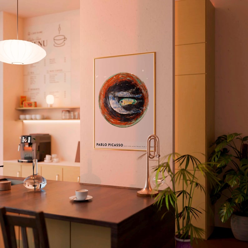 May include: A framed artwork featuring a circular abstract design with a fish in the center, attributed to Pablo Picasso. The artwork is displayed in a cafe setting, alongside a trumpet and a plant.
