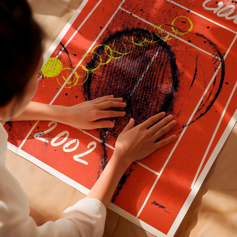 May include: A red poster with a black and white abstract design, featuring the year "2002" in white. The poster has yellow and black accents and is being held by a person.