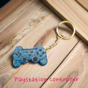 May include: A blue glitter PlayStation controller keychain with a gold chain and ring.