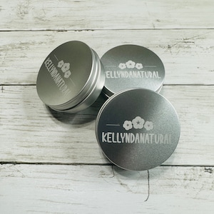 May include: Three silver metal tins with the text "KELLYNDANATURAL" and a stylized flower design engraved on the top.