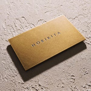 Puede incluir: Una tarjeta rectangular de color dorado con un acabado met&aacute;lico liso. La palabra HORIKITA est&aacute; grabada en letras may&uacute;sculas oscuras en el centro de la tarjeta, creando una apariencia limpia y profesional para este art&iacute;culo de papeler&iacute;a.