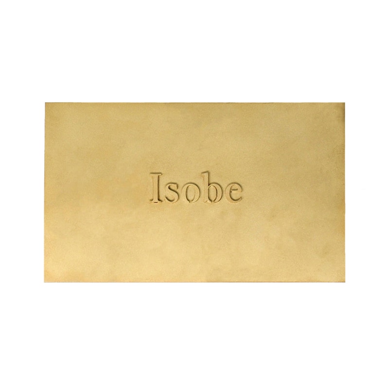 Puede incluir: Una placa rectangular de lat&oacute;n con un acabado dorado mate y liso. La palabra Isobe est&aacute; grabada en relieve en el centro de la placa con una fuente serif cl&aacute;sica. Los bordes de la placa de metal son rectos y limpios, creando una superficie plana.