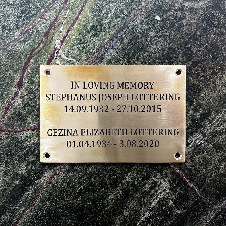 Puede incluir: Una placa conmemorativa rectangular de lat&oacute;n con cuatro orificios para tornillos en las esquinas, grabada con el texto: IN LOVING MEMORY, STEPHANUS JOSEPH LOTTERING 14.09.1932 - 27.10.2015, GEZINA ELIZABETH LOTTERING 01.04.1934 - 3.08.2020 en letras negras.