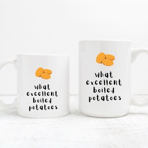 May include: Two white ceramic mugs with black text and a cartoon image of boiled potatoes. The text on the mugs reads "What excellent boiled potatoes".