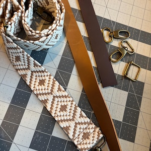 May include: A close-up of two leather straps and a woven strap with a geometric pattern. The straps are brown and white. There are also four metal clasps.