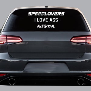Könnte beinhalten: Ein schwarzes Auto mit einem weißen Aufkleber auf der Heckscheibe, auf dem "SPEEDLOVERS", "LOVE ASS" und "ANTISOCIAL" steht.
