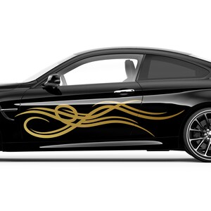 Könnte beinhalten: Ein schwarzes Auto mit einem goldenen Tribal-Grafikaufkleber an der Seite. Der Aufkleber ist ein stilisiertes Design von Wellen oder Flammen.