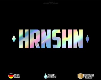 May include: A holographic sticker featuring the word "HRNSHN" in white lettering. The sticker has a diamond shape on each side. The sticker is displayed against a black backdrop.