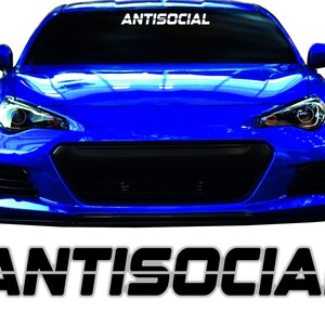 Könnte beinhalten: Ein blaues Auto mit einer schwarzen Frontstoßstange und einem weißen "ANTISOCIAL"-Aufkleber auf der Windschutzscheibe. Das Wort "ANTISOCIAL" wird auch in schwarzen Buchstaben auf einem grauen Hintergrund unter dem Auto angezeigt.