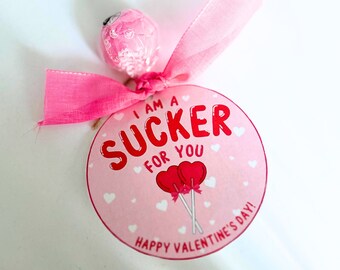 May include: Pink and red Valentine's Day card with the text "I am a sucker for you" and two red heart lollipops. The card also says "Happy Valentine's Day!"