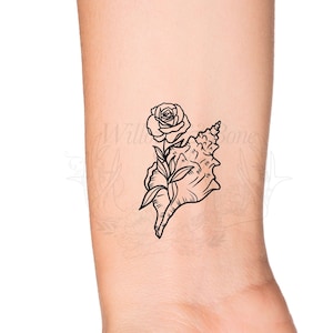 May include: A black and white line drawing tattoo design of a seashell with a rose growing out of it.
