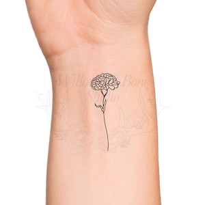 May include: A black line drawing of a carnation flower on a person's wrist.