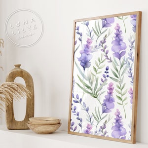 Op de afbeelding: Een ingelijst print met een aquarelpatroon van paarse en groene bloemen op een witte achtergrond. De lijst is van lichtbruin hout.