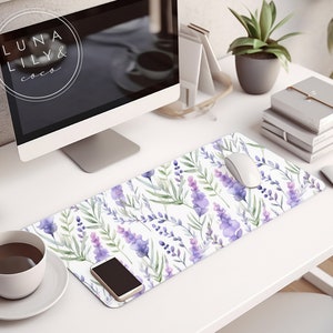 Op de afbeelding: Een wit bureau met een computermonitor, een kopje koffie, een potplant, een stapel boeken, een witte muis, een smartphone en een lavendelbloem muismat met de tekst "LUNA LILY & coco".
