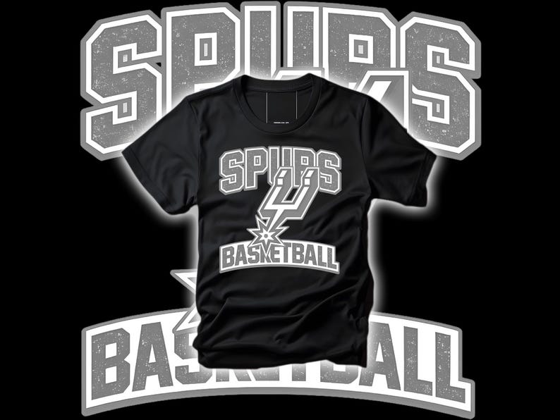 May include: Black t-shirt with the text "SPURS BASKETBALL" in white and gray. The shirt features the Spurs logo, a stylized "SPURS" wordmark, and a basketball graphic. The design is set against a black background.
