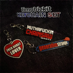 Può includere: Un set di tre portachiavi con vari disegni e testo. Uno è a forma di cuore con "FRED DURST LOVER". Un altro dice "MUTHAFUCKIN CHAINSAW WHAT?" e l'ultimo dice "generation strange".
