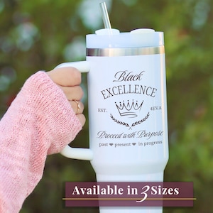 May include: White tumbler with a handle and a silver straw. The tumbler features the text "Black Excellence" with a crown graphic and the words "Proceed with Purpose." The tumbler is available in 3 sizes.