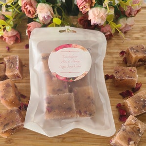 May include: A clear plastic bag filled with rose and honey sugar scrub cubes. The bag has a label that reads "Embodiedcare Rose & Honey Sugar Scrub Cubes".