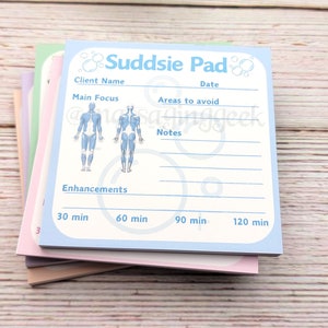 Puede incluir: Un bloc de notas azul y blanco con el título "Suddsie Pad" y un diagrama de contorno del cuerpo. El bloc de notas tiene secciones para el nombre del cliente, la fecha, el enfoque principal, las áreas a evitar, las notas y las mejoras. El bloc de notas también tiene una sección de tiempo con 30, 60, 90 y 120 minutos.