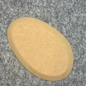 Könnte beinhalten: Ein ovaler Untersetzer aus hellem Holz mit glatter Oberfläche.