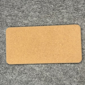 Könnte beinhalten: Ein rechteckiger Kork-Pinwand mit hellbrauner Farbe. Die Pinnwand ist aus einem natürlichen Material gefertigt und hat eine leicht raue Textur.
