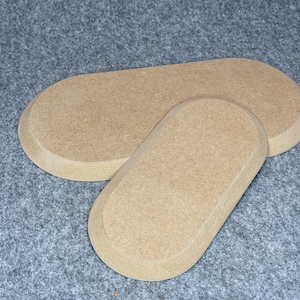 Könnte beinhalten: Zwei ovale, hellbraune Untersetzer aus Holz. Die Untersetzer bestehen aus einem rauen, strukturierten Material.