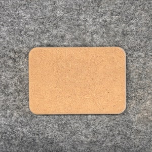 Könnte beinhalten: Ein rechteckiger Kork-Pinwand mit hellbrauner Farbe. Die Pinnwand ist aus einem natürlichen Material gefertigt und hat eine leicht raue Textur.