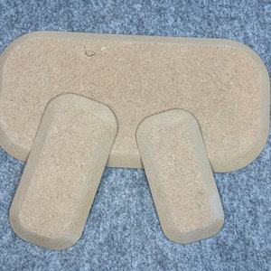Könnte beinhalten: Drei beige, rechteckige Holztabletts mit abgerundeten Kanten. Das größte Tablett befindet sich hinten und die beiden kleineren Tabletts davor.