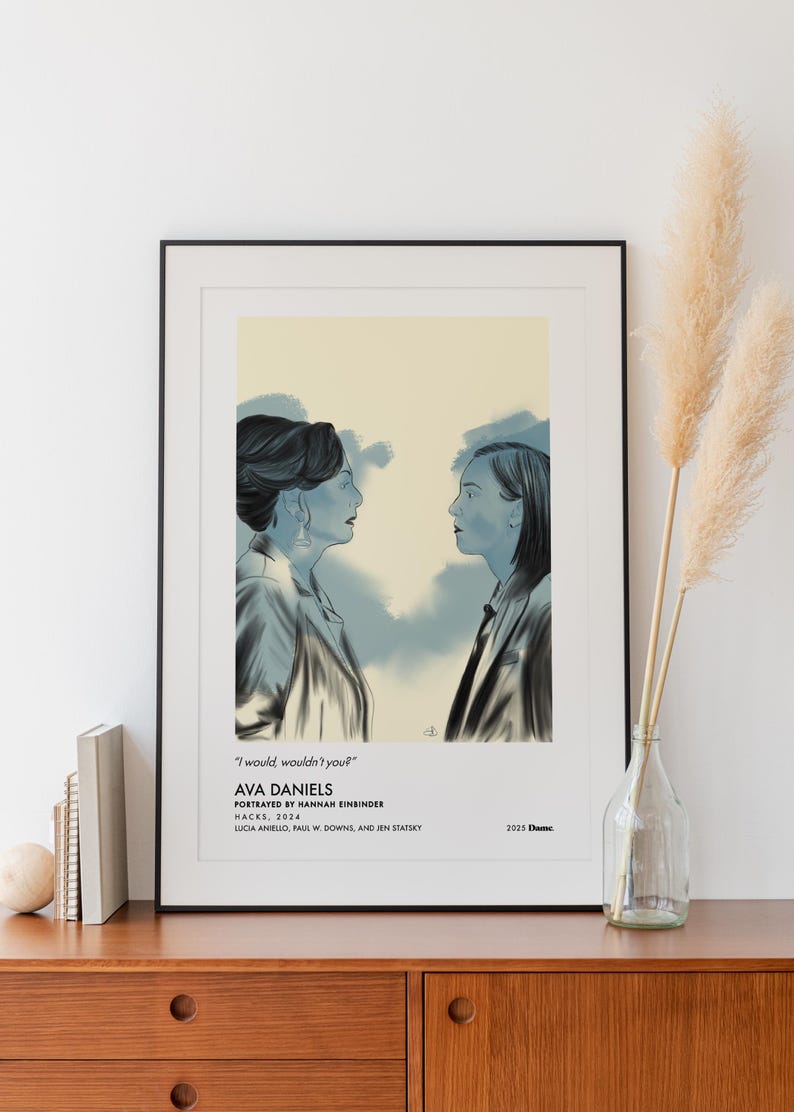 May include: A framed art print featuring a stylized illustration of two women facing each other. The artwork is in shades of blue and gray, with text that reads "I would, wouldn't you?" and "AVA DANIELS". The print is displayed on a wooden cabinet.